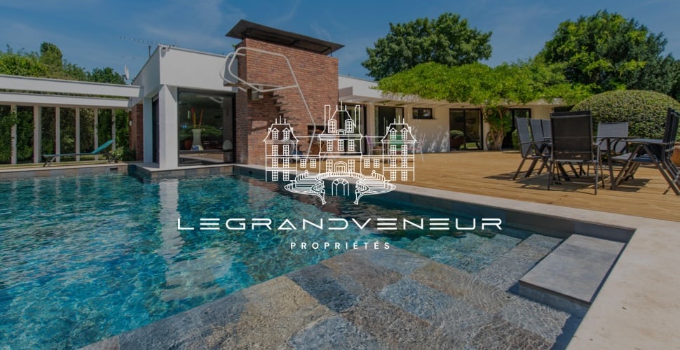 Image logo en blanc sur fond photo d’une belle maison avec piscine proposé par l’agence Legrandveneur : refonte visuelle pour de l’immobilier de luxe